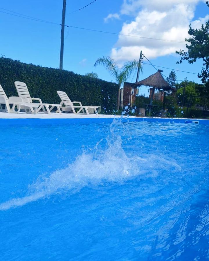 Salpicadura de agua en la piscina con reposeras al fondo