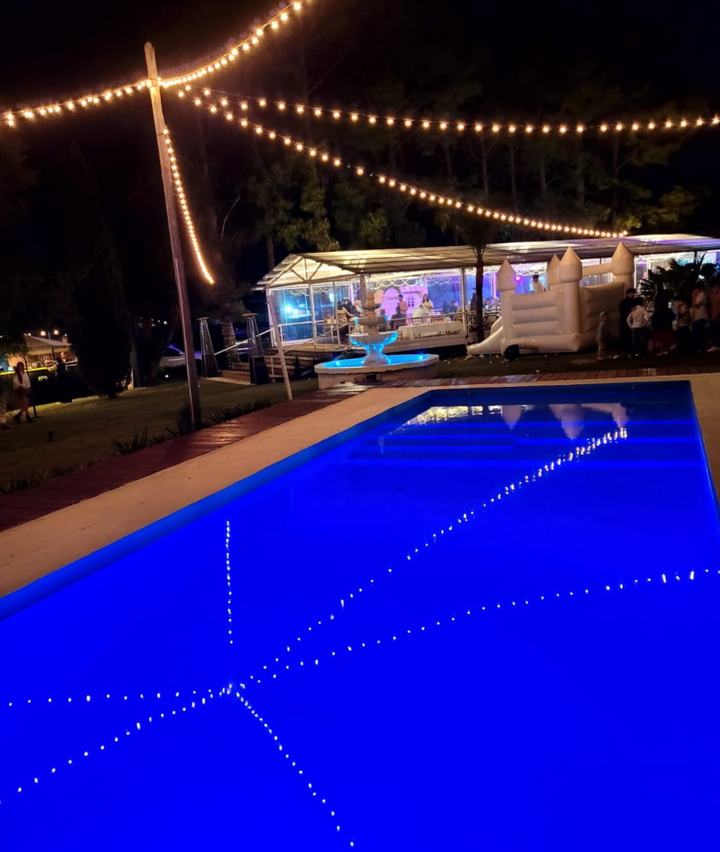 Piscina iluminada en azul con guirnaldas de luces